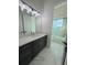 Bathroom with dark vanity, quartz countertop, and marble-tiled floor at 547 Sanctuary Golf Pl, Apopka, FL 32712