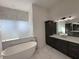 Spa-like bathroom with soaking tub, marble tile, and dark cabinetry at 547 Sanctuary Golf Pl, Apopka, FL 32712