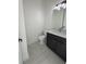 Modern powder room with dark vanity, white countertop, and gray tile floor at 547 Sanctuary Golf Pl, Apopka, FL 32712