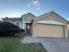 Tan one-story house with a two-car garage and lush landscaping at 556 Home Grove Dr, Winter Garden, FL 34787