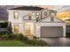 Two-story home with light-colored siding, a three-car garage, and landscaping at 200 Bottle Brush, Haines City, FL 33844