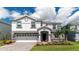 Two-story house with gray and white exterior, stone accents, and a three-car garage at 8823 Interlocking Ct, Davenport, FL 33896