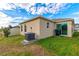 Tan house exterior with sliding glass doors, AC unit, and grassy backyard at 591 Preserve Pointe Blvd, Davenport, FL 33837