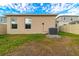Tan house exterior with windows, AC unit, and grassy backyard at 591 Preserve Pointe Blvd, Davenport, FL 33837