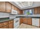 View of kitchen with wood cabinets, white appliances, and double sink at 6761 Trail Ridge Dr, Lakeland, FL 33813