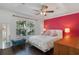 Main bedroom with pink accent wall, ceiling fan, and hardwood floors at 7321 Brightland St, Windermere, FL 34786