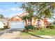 Inviting home with a two-car garage, landscaped yard, and palm trees at 167 Castaway Beach Way, Kissimmee, FL 34746