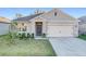 One-story home with light beige siding, dark gray door, and two-car garage at 3290 Logan Berry Dr, Mount Dora, FL 32757