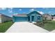 Two-car garage teal house with a landscaped front yard at 1963 Turtle Dove Ln, Kissimmee, FL 34746