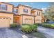 Tan townhome with attached garage, landscaping, and a paved driveway at 2020 Retreat View Cir, Sanford, FL 32771