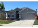 Gray house with a two-car garage and lush landscaping, showcasing palm trees at 10198 Oak Crest Rd, Orlando, FL 32829