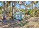 A light teal shed with white doors in a backyard setting at 3420 Lake Harney Cir, Geneva, FL 32732