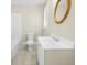 Simple bathroom with white fixtures, tiled floor, and a round mirror at 1271 6Th St, Clermont, FL 34711