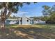 Spacious backyard with a large tree and a gray house at 27623 Lisa Dr, Tavares, FL 32778
