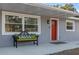 Inviting front porch with a red door and a bench, showcasing curb appeal at 27623 Lisa Dr, Tavares, FL 32778