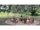 Rustic fire pit with seating area under shade trees at 12039 Lakeshore Way, Oxford, FL 34484