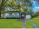 Gray house with a white garage, red door and nicely landscaped lawn at 20 Maynard Ave, Orlando, FL 32803