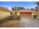 Front view of a single-story home with a brown garage door and well-manicured landscaping at 5027 Jamaica Cir # 7, Orlando, FL 32808