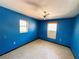 Simple bedroom with blue walls, two windows, and ceiling fan at 6301 State Road 60 E, Bartow, FL 33830