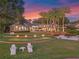 Backyard with illuminated putting green, pool, spa and lake views at dusk at 100 Blue Lake Ct, Longwood, FL 32779