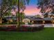 Luxury waterfront home exterior at sunset with lush landscaping and a three-car garage at 100 Blue Lake Ct, Longwood, FL 32779