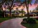 Paver driveway leading to a beautiful home at sunset, surrounded by trees and landscaping at 100 Blue Lake Ct, Longwood, FL 32779