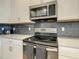Modern kitchen with stainless steel appliances and dark gray backsplash at 1670 Moon Valley Dr, Davenport, FL 33896