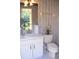 Powder room with white vanity, toilet, and updated wallpaper at 772 Bear Creek Cir, Winter Springs, FL 32708