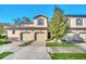 Two-story townhome with two-car garage and a tree in front at 8169 Roseville Rd, Davenport, FL 33896