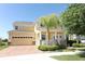 Two-story house with a beige exterior, brick driveway, and palm tree at 15121 Evergreen Oak Loop, Winter Garden, FL 34787