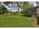 Large backyard with lush lawn, mature trees, and screened-in pool at 25510 High Hampton Cir, Sorrento, FL 32776