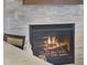Close-up of a modern fireplace with a gray stone surround and a crackling fire at 25510 High Hampton Cir, Sorrento, FL 32776