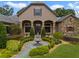 Inviting front yard with a stone fountain, lush landscaping, and a charming walkway at 25510 High Hampton Cir, Sorrento, FL 32776