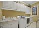 Spacious laundry room equipped with white cabinets, washer, dryer, and sink at 25510 High Hampton Cir, Sorrento, FL 32776