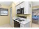 Compact kitchen with black appliances, white cabinets, and a window at 445 Bouchelle Dr # 202, New Smyrna Beach, FL 32169