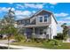 Two-story house, gray siding, stone accents, landscaping, and a two-car garage at 12027 Language Way, Orlando, FL 32832