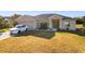 Tan house with gray roof, double door entry, and a white car parked in the driveway at 1218 Coda Ct, Dundee, FL 33838