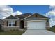 One-story home with a two-car garage, and a brown and white exterior at 2952 Waterlily Way, Poinciana, FL 34759