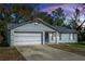 Gray house with white garage door and blue shutters, at dusk at 1073 Humphrey Blvd, Deltona, FL 32738