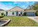One-story house with a gray door, attached garage, and well-manicured lawn at 1812 Hudson Ct, Kissimmee, FL 34759