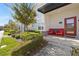 Inviting front porch with red door and chairs, lush landscaping, and modern exterior at 200 Ocean Course Ave, Davenport, FL 33896