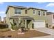 Two-story green house with palm tree, white garage door, and small lawn at 2665 Magnolia Ave, Davenport, FL 33837