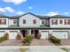 Two-story townhome with gray siding, red shutters, and a brick driveway at 308 Rustic Loop, Sanford, FL 32771