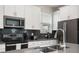 Close-up of the kitchen featuring stainless steel appliances, dark tile backsplash, and white cabinets at 8942 Cabot Cliffs Dr, Davenport, FL 33896