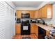 Kitchen features wood cabinets, black appliances, and tile floor at 2310 Fairgren Ave, Deltona, FL 32738