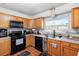 Bright kitchen with wood cabinets, black appliances, and tile floor at 2310 Fairgren Ave, Deltona, FL 32738