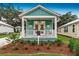 Charming cottage with light teal exterior, front porch, and landscaping at 12133 Grand Oak Ln, Oxford, FL 34484