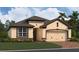 Tan and brown one-story home with two-car garage and front yard at 5298 Teirgarten St, St Cloud, FL 34771