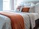 Bright bedroom with orange throw and geometric patterned wallpaper at 8933 Amelia Downs Trl, Kissimmee, FL 34747