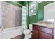 Bathroom with tiled shower, granite vanity, and green accent wall at 2731 Flintlock Ave, Clermont, FL 34711